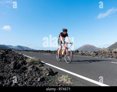 Radfahrer reiten durch den Nationalpark Timanfaya auf Lanzarote, Kanarische Inseln, Spanien Stockfoto