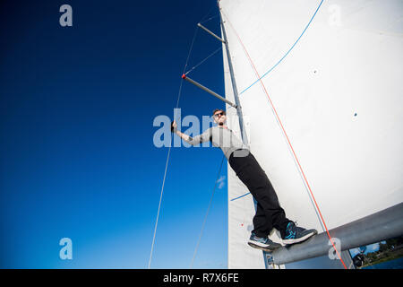Low Angle View von lächelnden Mann stand auf der Yacht boom Stockfoto