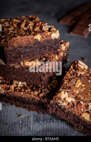 Köstliche Brownies mit Walnüssen, die in einem Stapel auf einen hölzernen Tisch. Nahaufnahme mit Schokoladenkuchen Kuchen geschnitten Stück Stockfoto