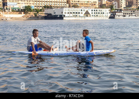 Assuan, Ägypten - September 13, 2018: Ägyptische Kinder in einem Surf Board im Nil. Stockfoto