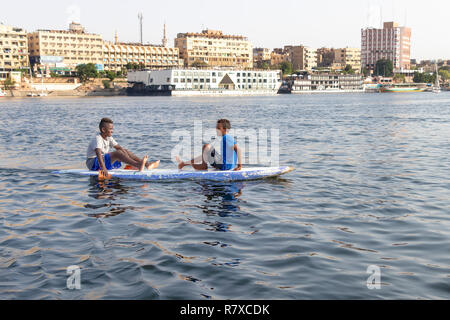 Assuan, Ägypten - September 13, 2018: Ägyptische Kinder in einem Surf Board im Nil. Stockfoto