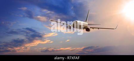 Kommerzielle Flugzeug fliegen über Wolken in dramatischen Abendlicht Stockfoto