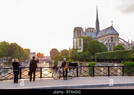 Frankreich, Paris, ein Saxophonist auf der Brücke des Erzbischofs und Notre Dame de Paris. Stockfoto