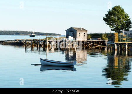 Blick auf Bass Harbor Maine aus dem Deck Thurston's Lobster Pound mit einem Dock, Hummer, fallen, Boot Haus, Baum und Ruderboot Reflexionen sichtbar. Stockfoto