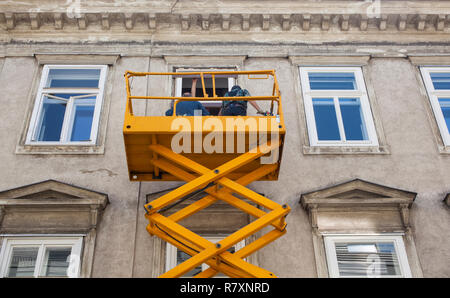 Wien, ÖSTERREICH - Mai 22: Arbeitnehmer mit auf einen gelben Cherry Picker die Fassade eines Gebäudes am 22. Mai 2018 sanieren Stockfoto