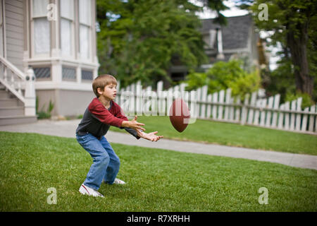 Junge hockend ein Fußball im Vorgarten seines Hauses zu fangen. Stockfoto