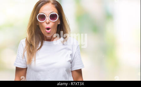 Mittleres Alter Hispanic Frau tragen Mode Sonnenbrillen über isolierte Hintergrund Angst und mit Erstaunen Ausdruck, Angst und aufgeregt Gesicht schockiert. Stockfoto