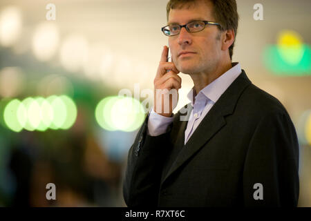 Mitte der erwachsenen Mann hält ein Handy am Ohr. Stockfoto