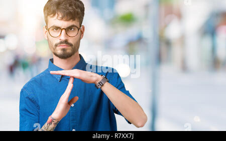 Jungen gutaussehenden Mann Brille über isolierte Hintergrund tun time out Geste mit den Händen, frustriert und ernstes Gesicht Stockfoto