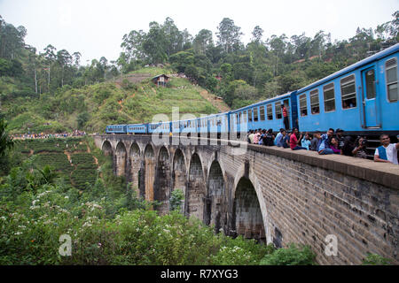 Demodara, Sri Lanka - August 5, 2018: die Menschen neben einem blauen Zug Überqueren der berühmten neun Bogenbrücke Stockfoto