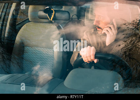 Vorderansicht des Menschen fahren Auto und Gespräch am Handy, die gefährlich ist und rücksichtslosen Verhaltens Stockfoto