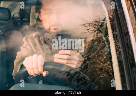 Vorderansicht des Menschen fahren Auto und SMS auf Handy, das ist gefährlich und rücksichtslos verhalten Stockfoto