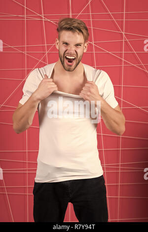 Mode Mann ziehen t-shirt Kragen mit Zorn. Fashion Model im lässigen Stil schreien auf rosa Hintergrund. Stockfoto