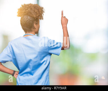 Junge afrikanische amerikanische Ärztin Frau über isolierte Hintergrund posiert rückwärts hinter zeigt mit Finger hand Stockfoto