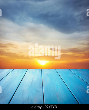 Blau Holztisch auf orange Sonnenuntergang Himmel Hintergrund Stockfoto