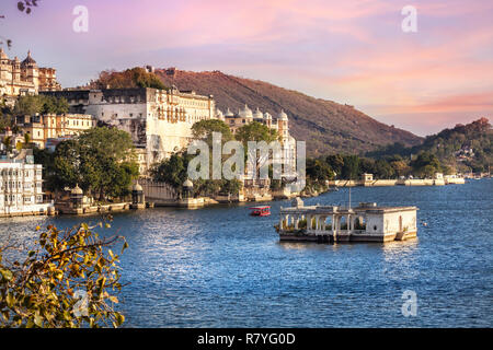 See Pichola mit City Palace Blick auf rosa Sonnenuntergang Himmel in Udaipur, Rajasthan, Indien Stockfoto