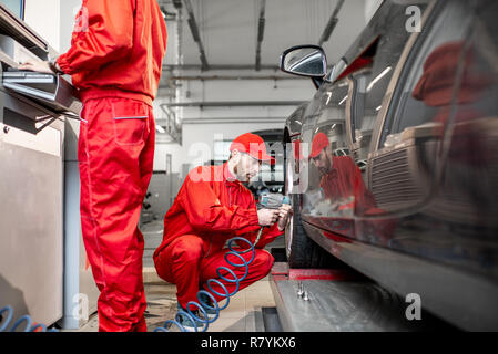 Zwei Auto service Arbeitnehmer in roter Uniform ändern Rad eines Sport Auto auf den Reifen Montage Service Stockfoto