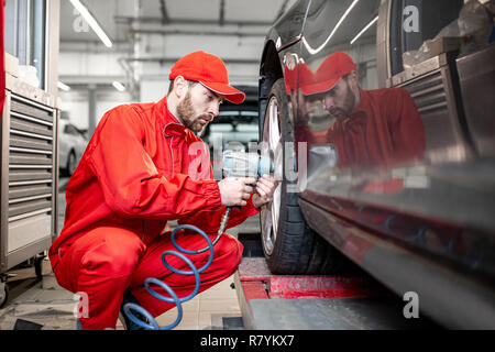 Ar service Arbeitnehmer in roter Uniform ändern Rad eines Sport Auto auf den Reifen Montage Service Stockfoto