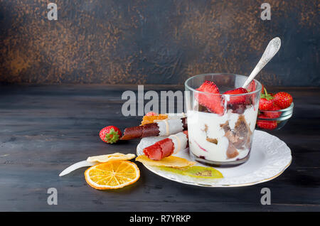 Schokolade Cookies, Sahne und Erdbeeren Nachtisch in einem Glas auf einem darkbackground, leckere Kleinigkeit, Kopie Raum Stockfoto