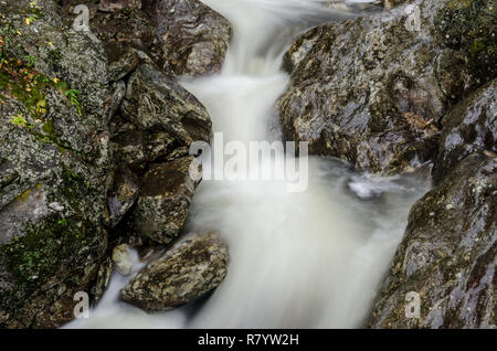 Eine lange Belichtung geschossen von einer ländlichen stream Gießen über Granitfelsen Stockfoto