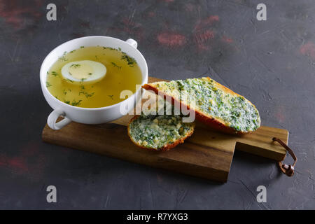 Klare Hühnerbrühe mit ei mit toast serviert. Stockfoto