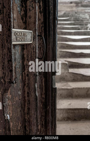 Ein kleines Schild auf der alten Holztür zeigt den Weg zu den historischen Kapitel Haus schritte bei Wells Cathedral in Somerset. Stockfoto