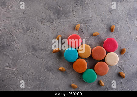Macarons in Form von Herzen und Mandel Muttern auf einen strukturellen Hintergrund. Flach. Ernährung Konzept. Raum unter dem Text. Stockfoto