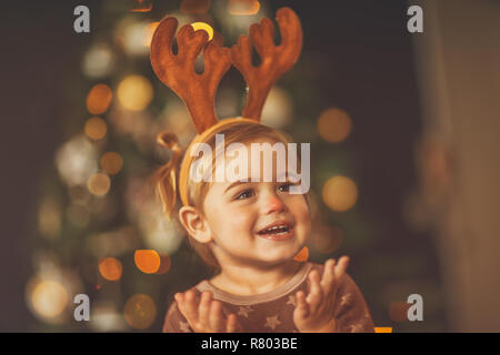 Porträt einer niedlichen kleinen Baby Boy tragen roten Nase rudolph Kostüm, über schönes Bokeh Lichter des Weihnachtsbaums schoß, Spaß auf der matine Stockfoto
