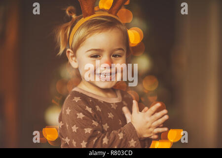 Portrait Of Happy little boy tragen Festliche raindeer Hörner, Rudolph mit der roten Nase, fröhliches Baby klatschen der Freude Stockfoto