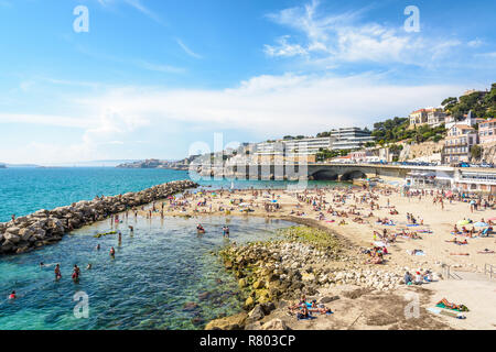 Menschen mit Sonnenbaden und Schwimmen auf der Prophet Strand in Marseille, einem sehr beliebten Strand auf dem Kennedy Corniche entfernt, an einem sonnigen Frühlingstag. Stockfoto