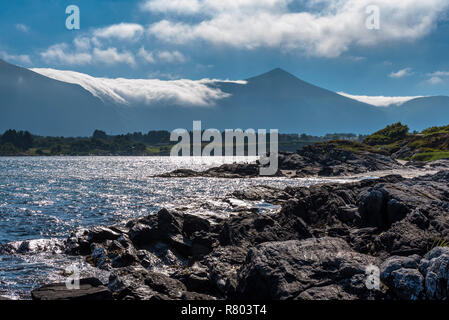 Schöne Sicht auf die Norwegischen felsigen Atlantikküste mit Wolken und Nebel bedeckte Berge im Hintergrund. Norwegen, um hustad. Stockfoto