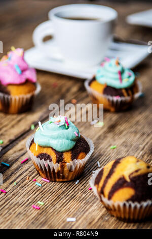 Chocolate Cupcake mit farbigen Rosa und grün Creme auf Holz Tisch Stockfoto