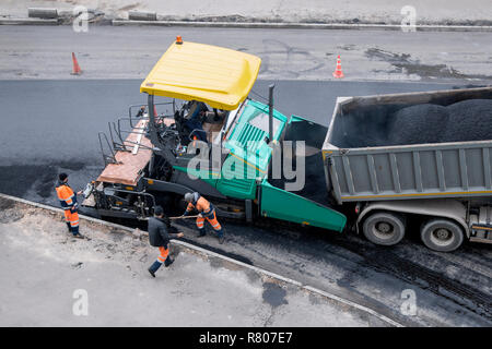 Ein Pflasterstein Maschine oder fertiger Finisher Orte eine Schicht von frischem Asphalt. Nicht erkennbare Arbeitnehmer. Straßenbau arbeiten, Erneuerung Stockfoto