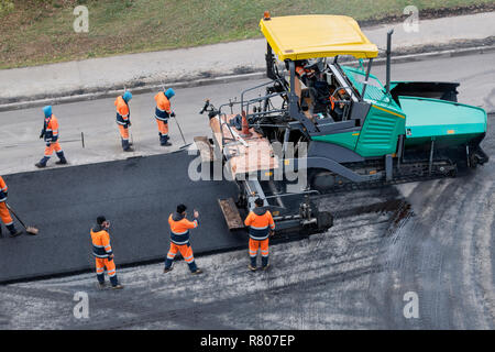 Asphalt fertiger Maschine oder fertiger Finisher Orte eine Schicht von frischem Asphalt. Straße Erneuerung, Bau arbeiten. Collage, unkenntlich Arbeitnehmer. Stockfoto