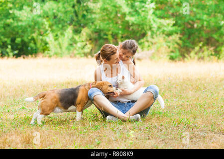 Junge Mutter und ihre Tochter spielen mit ihrer Katze und Hund Stockfoto