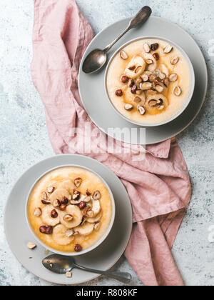 Zwei Schüssel mais Grieß Brei mit Banane, Haselnuss und verbrannte Butter Honig. Süße Polenta oder maismehl Brei. Ideen und Rezepte für sehr schnelle Kinder Frühstück. Top View oder flach. Platz kopieren. Vertikale Stockfoto