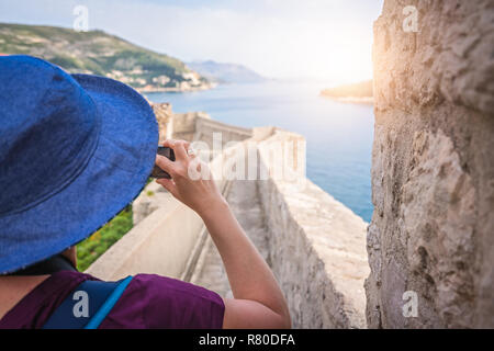 Kaukasische Frau mit einem blauen Hut, die Bilder von den historischen Mauern der Altstadt von Dubrovnik, Kroatien im Sommer Stockfoto