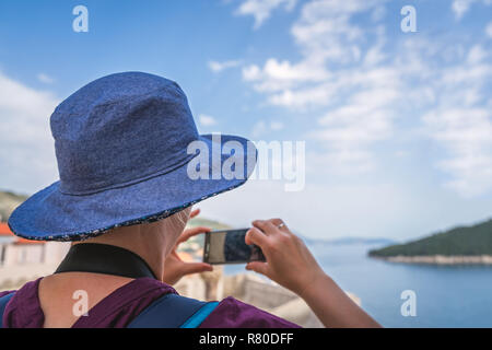 Kaukasische Frau mit einem blauen Hut, die Bilder von den historischen Mauern der Altstadt von Dubrovnik, Kroatien im Sommer Stockfoto