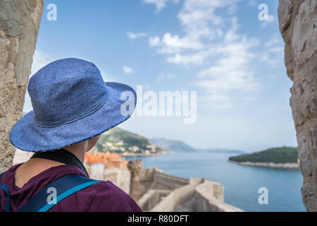 Kaukasische Frau mit einem blauen Hut gehen auf einem historischen Mauern der Altstadt von Dubrovnik, Kroatien im Sommer Stockfoto