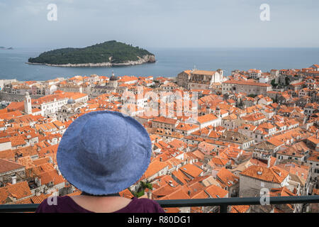 Kaukasische weiblichen Touristische wearnig blauen Hut auf der alten Stadtmauer in Dubrovnik mit Blick auf die historische Stadt unten, Kroatien Stockfoto