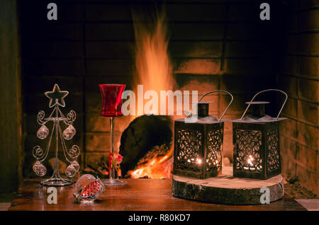 Weihnachten Komposition mit Laternen, Crystal Christmas Tree, rot Likör Glas und Granatapfel. Die Flamme der Kamin im Hintergrund. Stockfoto