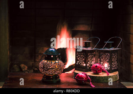 Weihnachten Komposition mit Laternen und Red Christmas Ornamente. Die Flamme der Kamin im Hintergrund. weihnachtliche Stimmung, festliche Atmosphäre. Stockfoto