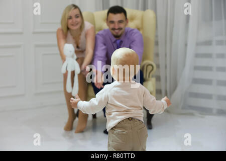 Das Kind läuft auf die Mutter und der Vater, der die Hände zieht. Junge Familie. Kind und Eltern Stockfoto