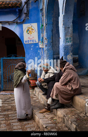 Marokko, Fes, blaue Stadt, Ort El Mazjen, alte Männer in djellabas saß im Gespräch mit lokalen Frau Stockfoto