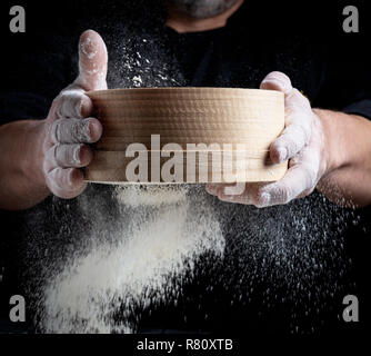 Man siebt weißes Mehl durch ein Sieb, in der Nähe Stockfoto