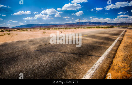 Schwarze asphalt Autobahn mit Windstoß bläst Rot Sand über Inthe Northern Arizona Wüste in der Mitte von Nirgendwo Stockfoto