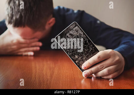 Kerl mit Borsten, zeigt seine Hand auf einem Smartphone. Stockfoto