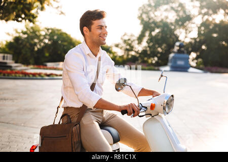Glückliche junge Unternehmer sitzen auf einem Motorrad im Freien fern suchen Stockfoto