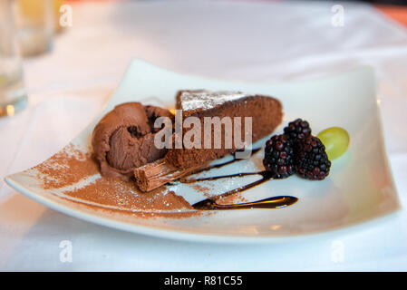 Brownie Kuchen mit Schokoladeneis und Brombeeren auf die weiße Platte mit Schokolade. Stockfoto