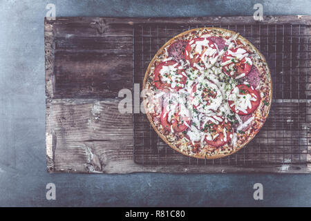 Leckere salami Pizza und kochen Zutaten Tomaten Basilikum auf einem Hintergrund. Ansicht von oben Stockfoto